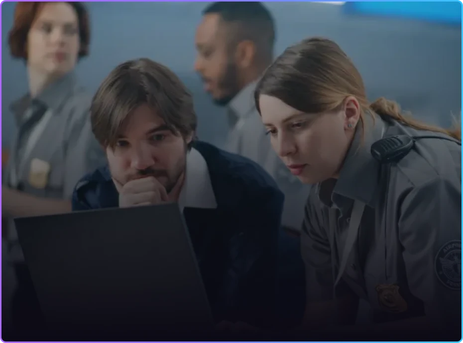 Two law enforcement officers reviewing information on a laptop during a team briefing
