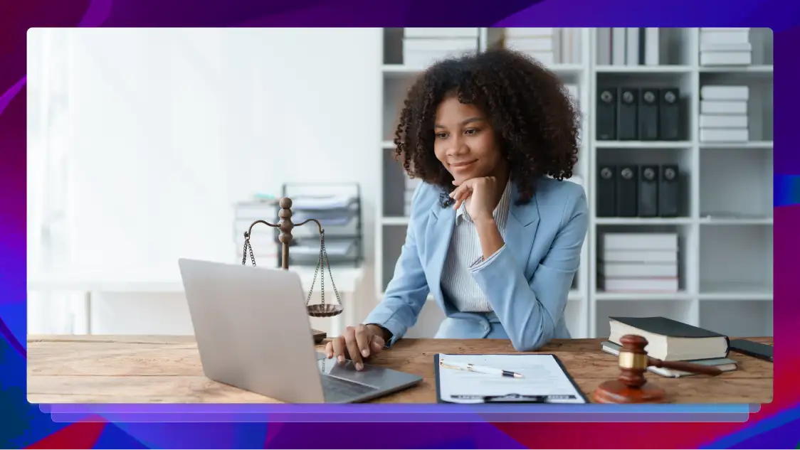 A woman working on a laptop in a law office, with shelves of law books behind her and a wooden gavel on the desk